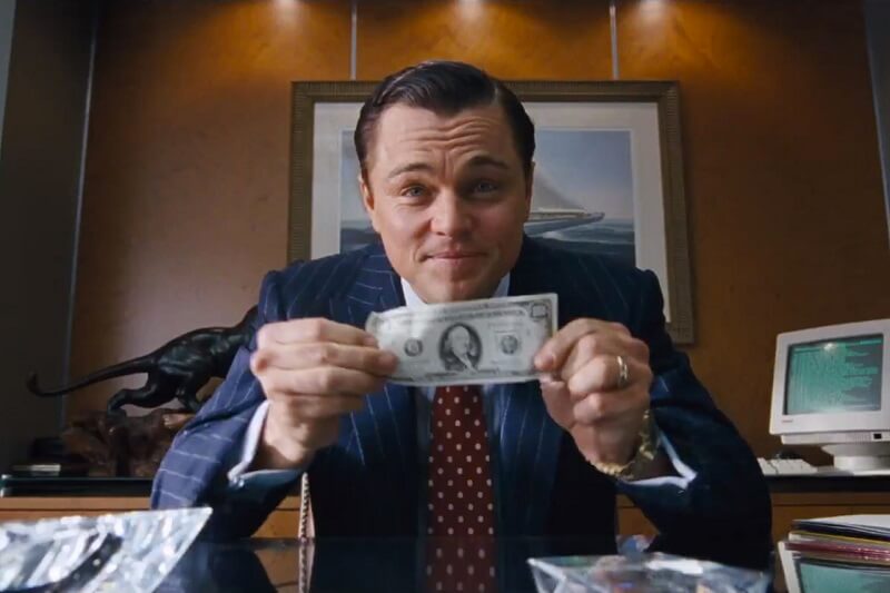 A képen egy jelenet látható a Wall Street farkasából. DiCaprio egy 100 dollárost tart a kezében